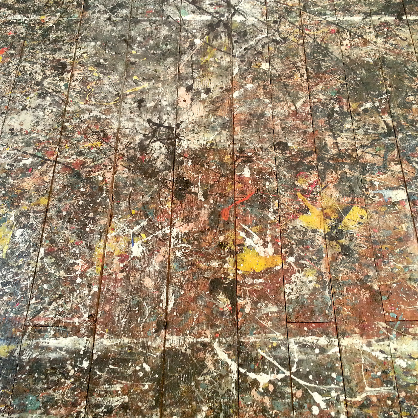 Art poster showing the paint-splattered floor of Jackson Pollock's studio, with modern typography