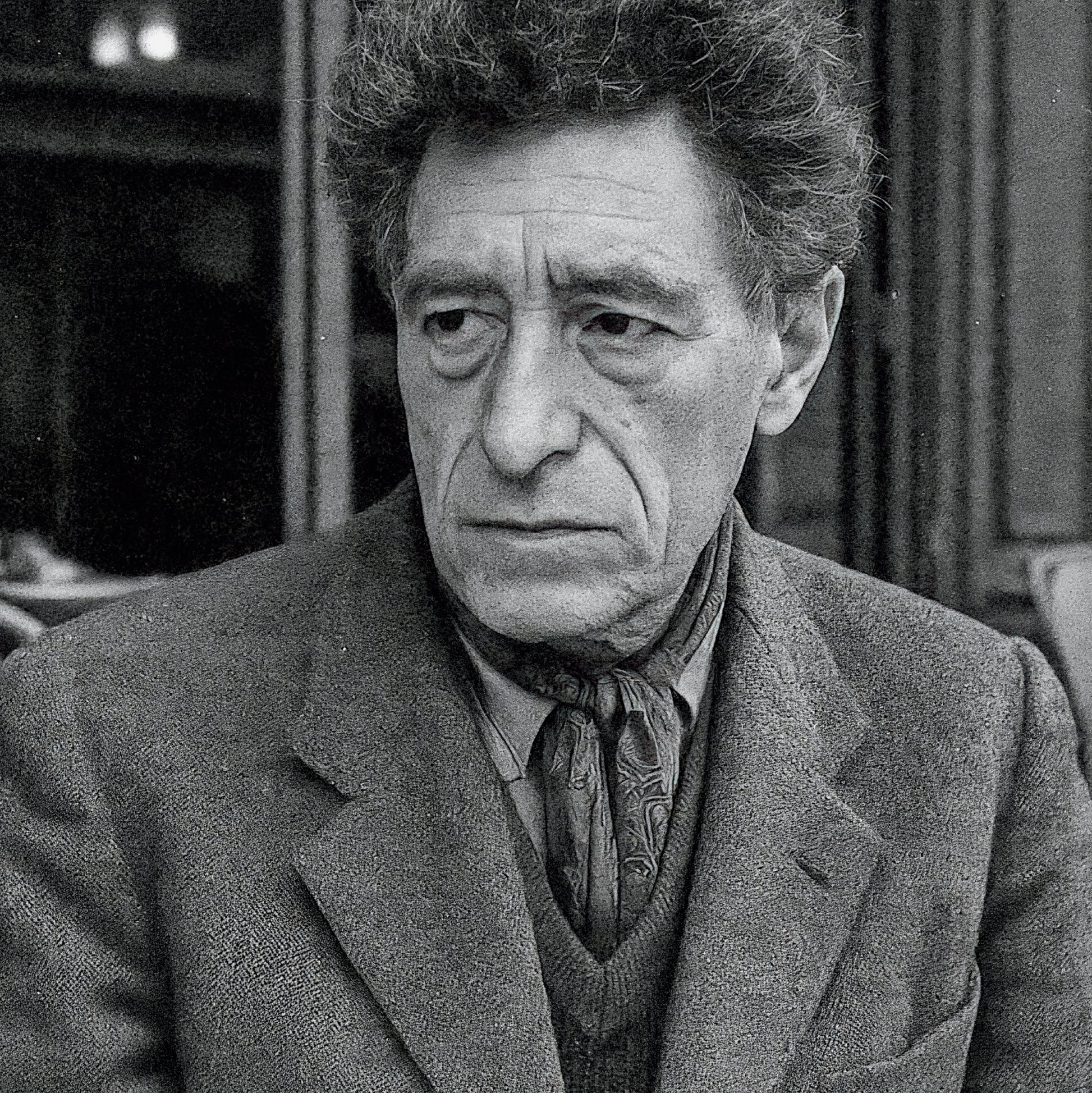 Black and white portrait of a man wearing a coat and patterned tie.