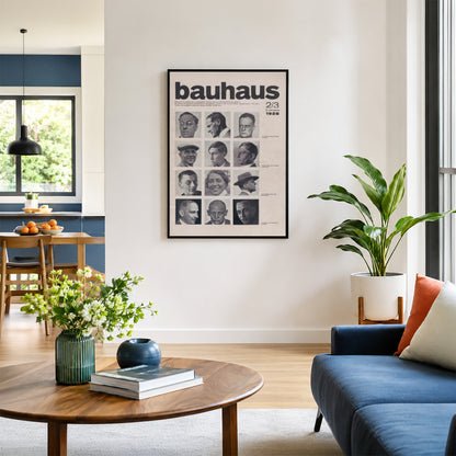 A framed Bauhaus 1923 poster hangs on a white wall in a modern living room setting with a blue sofa, wooden coffee table, and a potted plant.