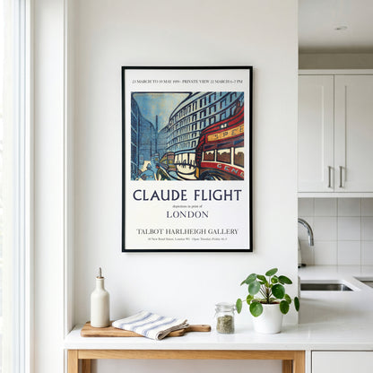 A framed vintage-style travel poster for Claude Flight in London hangs on a white kitchen wall above a countertop with a bottle, cloth, and small plant.