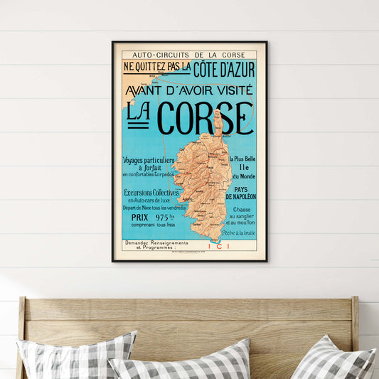 Framed map poster of Corsica on a wall above a bed with checkered pillows.