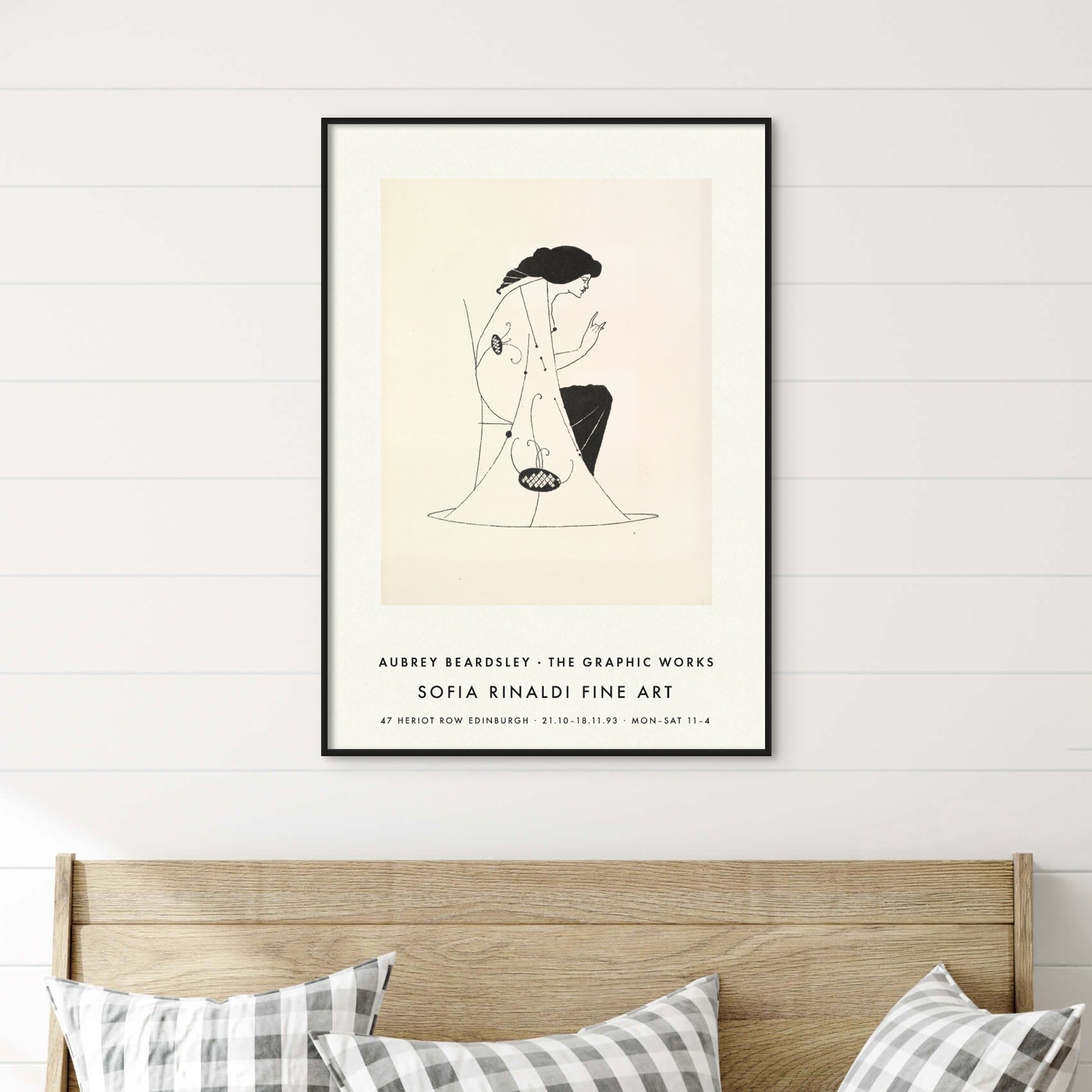Framed Aubrey Beardsley 'Seated Lady' Art Nouveau poster above a wooden bed with checked cushions