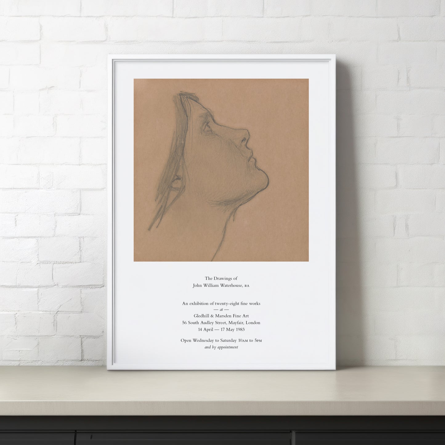 Framed artwork of a profile drawing on a beige background with text on a white wall.
